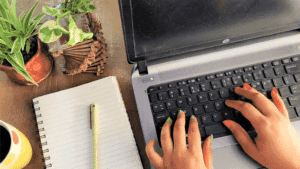 Hands typing on a keyboard with succulents nearby